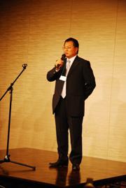 ステージ上でスピーチを行っている男性の写真