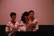 揃いの衣装でスピーチを行っている3人の女性の写真