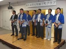 壇上で法被姿の男性たちがスピーチを行っている様子の写真