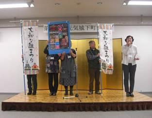 壇上で「大和な雛まつり」のPRを行っているスタッフたちの写真
