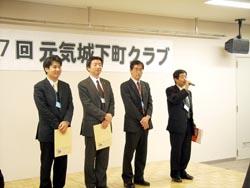 壇上で緊張気味のスーツ姿の男性たちの写真