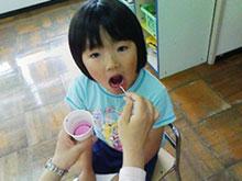 口を開け歯をピンクに染めてもらっている女の子の写真