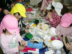 机の上の色々な工作道具を使っている子供の写真