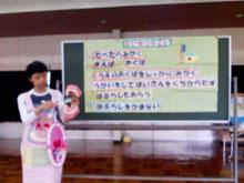 歯の磨き方について保育園児たちに黒板を使って指導する保健師さんの写真
