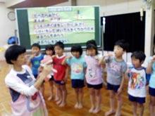 保育園児たちに保健師さんが歯の模型を使って磨き方を説明している写真
