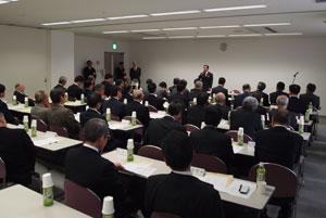 会議室内で大勢の人々が会合に参加している写真