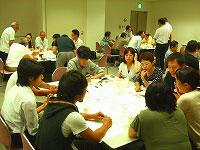 ワークショップ会場の全景写真。会場にはいくつかのデスクが設けられ、それらを囲んで複数のグループに分かれて意見を交換する様子が確認できる