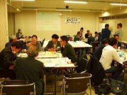 ワークショップ会場の全景写真。会場にはいくつかのデスクが設けられ、それらを囲んで複数のグループに分かれて意見を交換する様子が確認できる