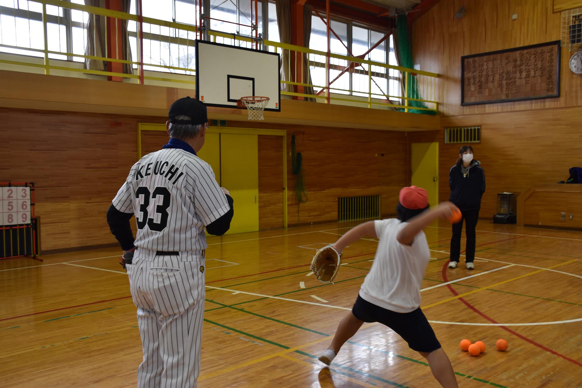 なげ方を指導する、元タイガース池内豊さんとボールを投げる男子児童