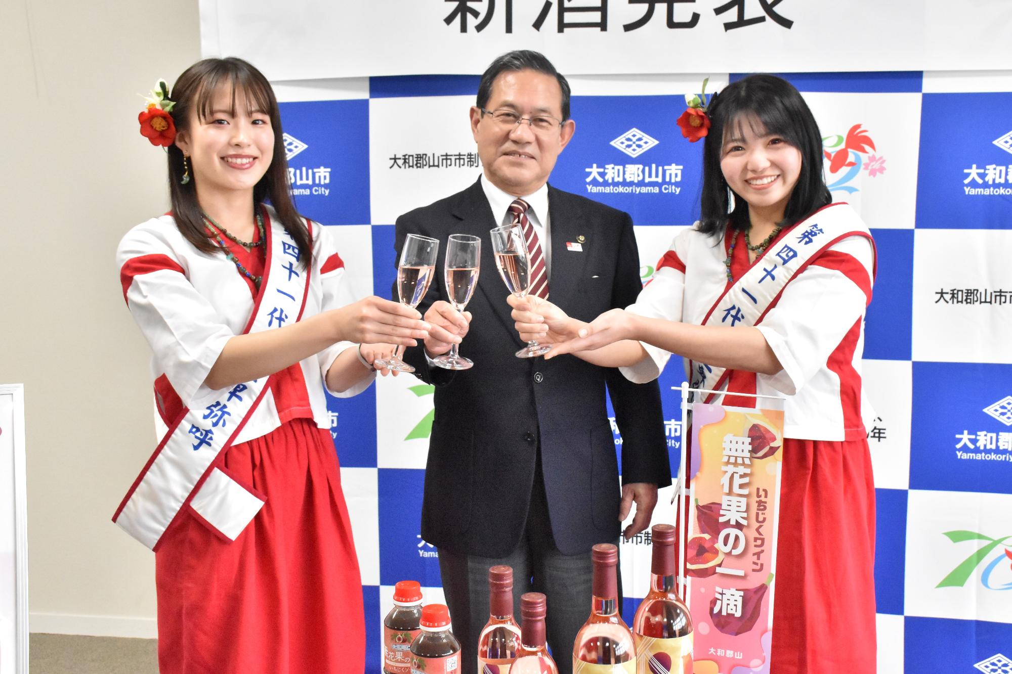 いちじくワイン「無花果の一滴」新酒を持ち、上田市長と女王卑弥呼が乾杯をしている様子