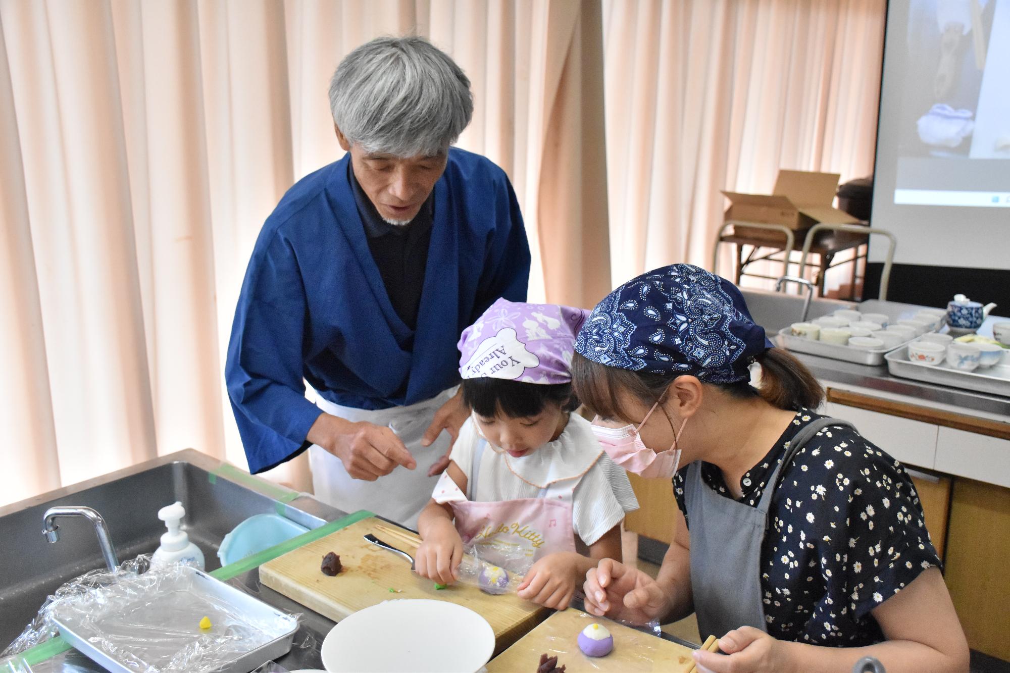 金魚和菓子作り講座で講師から和菓子作りを教わる親子