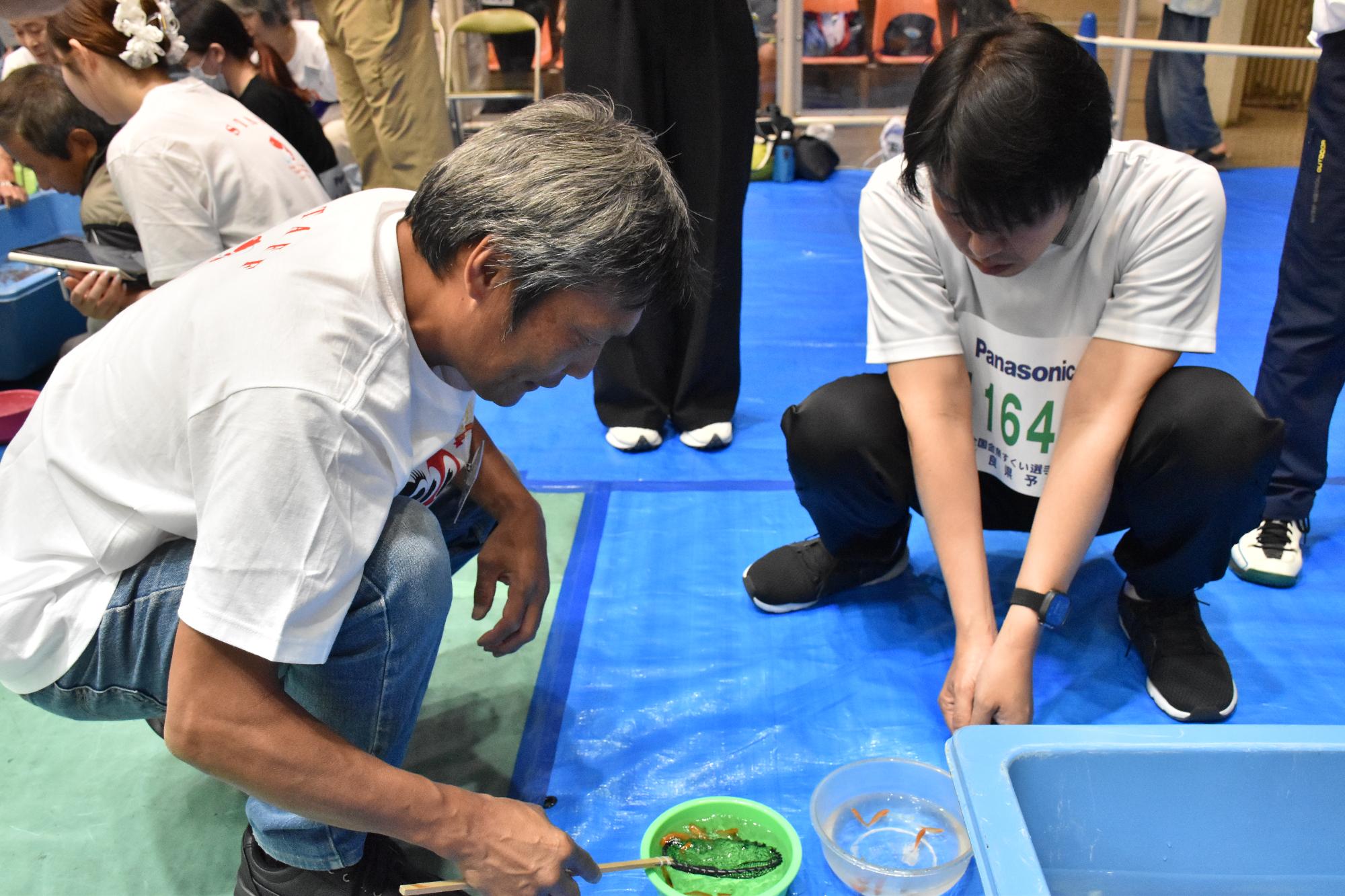全国金魚すくい選手権大会 金魚の匹数を数える審判員と参加者