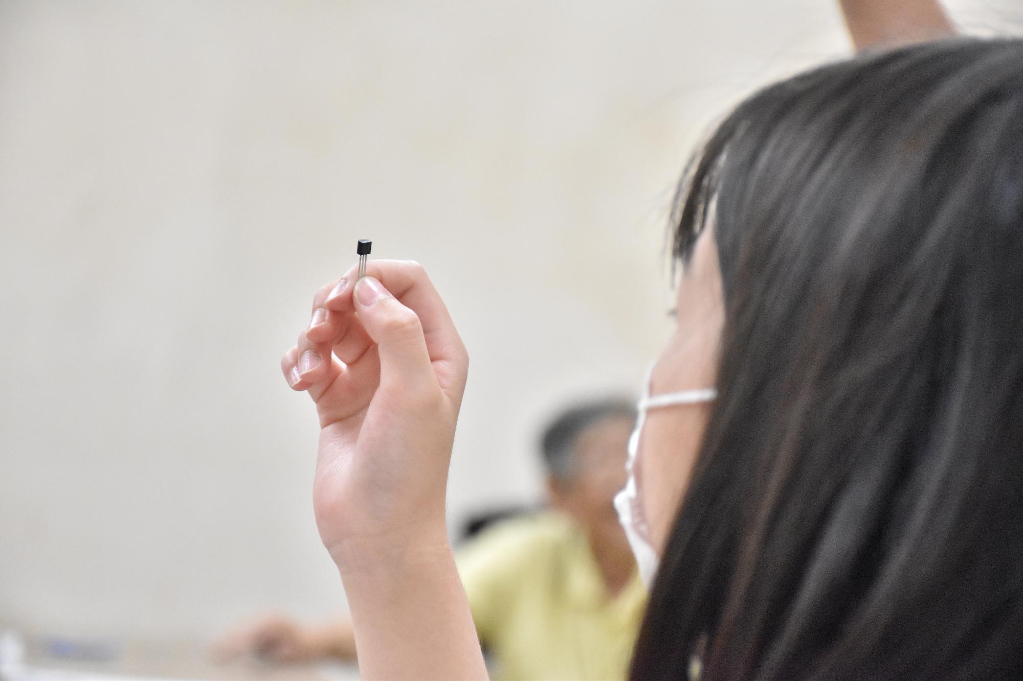 科学教室で工作に使うIC手に持ってを眺める参加者