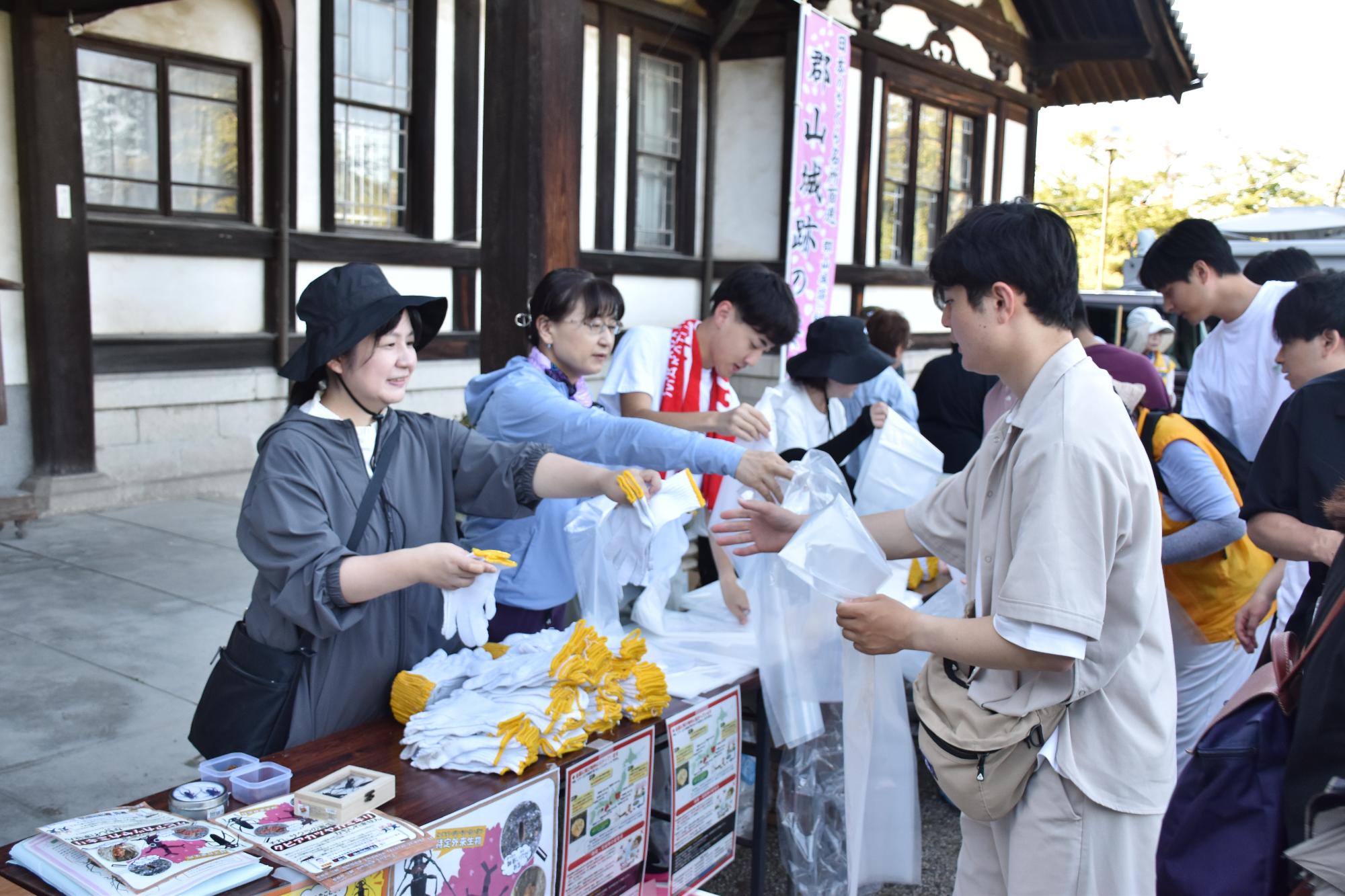 郡山城跡「桜」保存会の城内一斉清掃で掃除道具を受け取る参加者