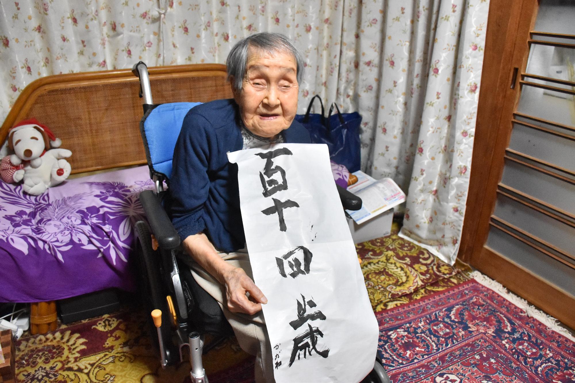 自身で書いた書道の作品を手にする賀川さん