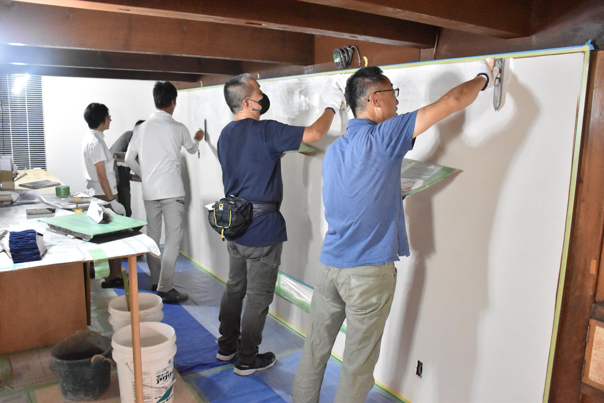 ワークショップで左官作業を体験する4人の参加者