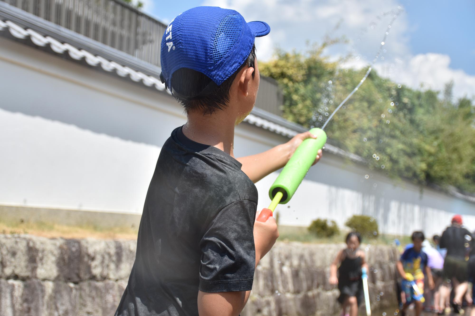 思い出に残る夏祭りで水鉄砲をする子ども