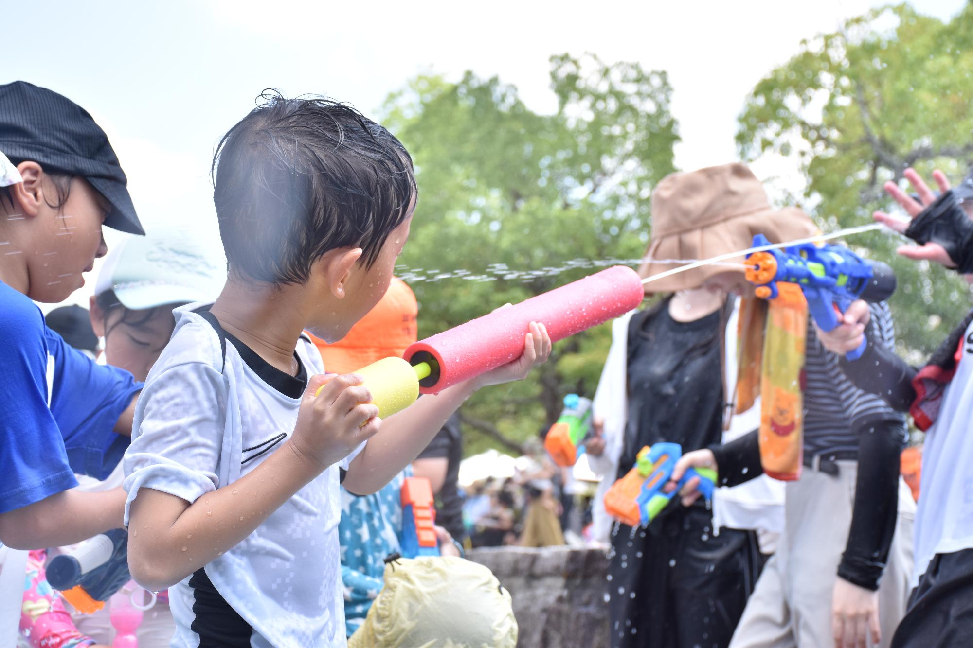 思い出に残る夏祭りで水鉄砲をする子ども
