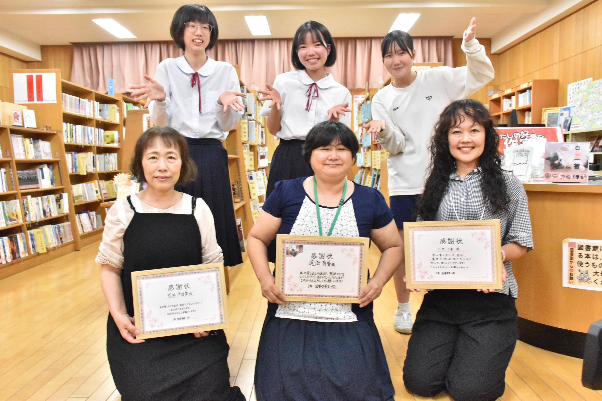 図書館ボランティアと図書委員が感謝状を持って記念撮影