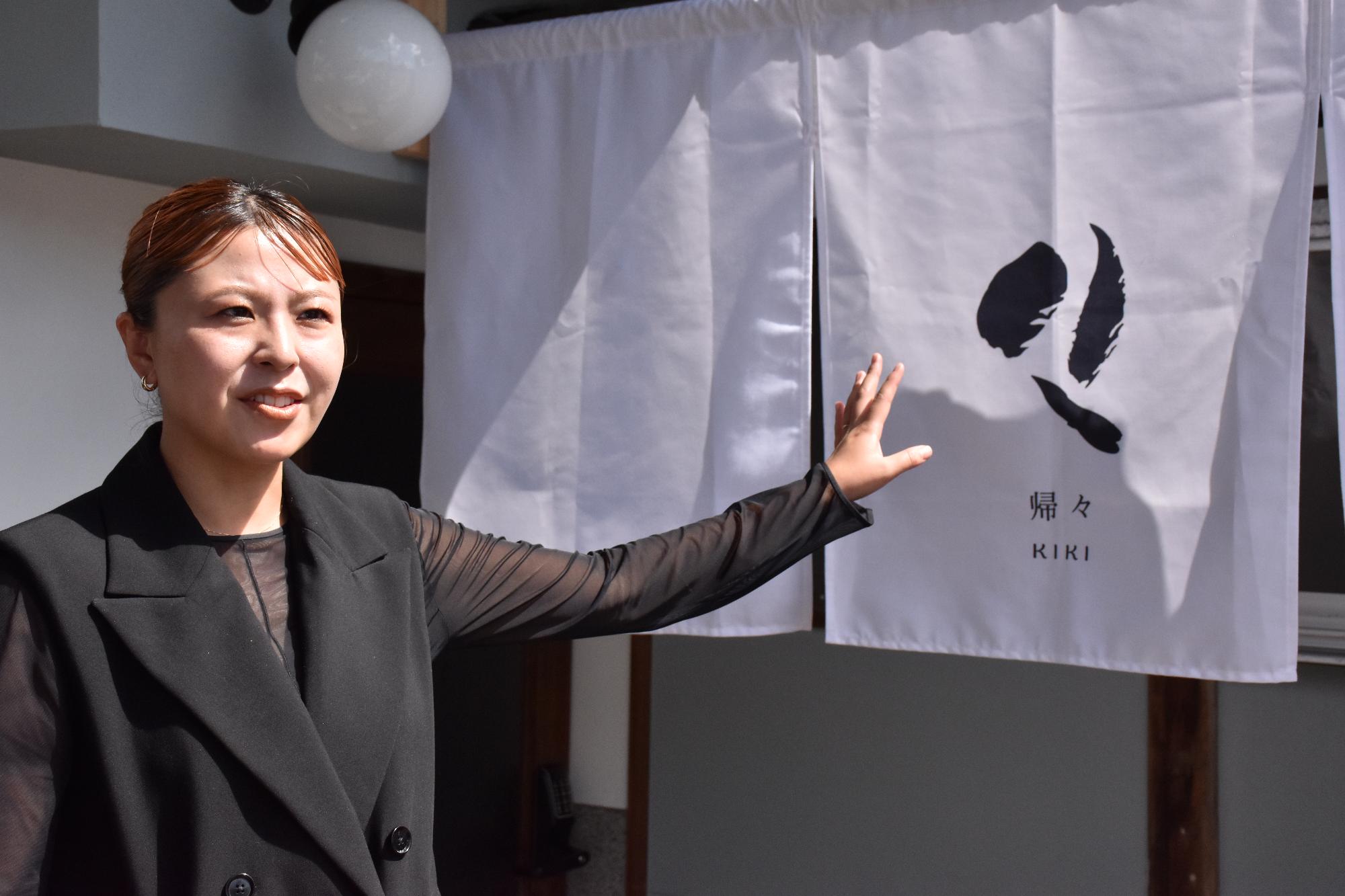 一棟貸しの宿泊施設「帰々」のロゴについて説明をする女性