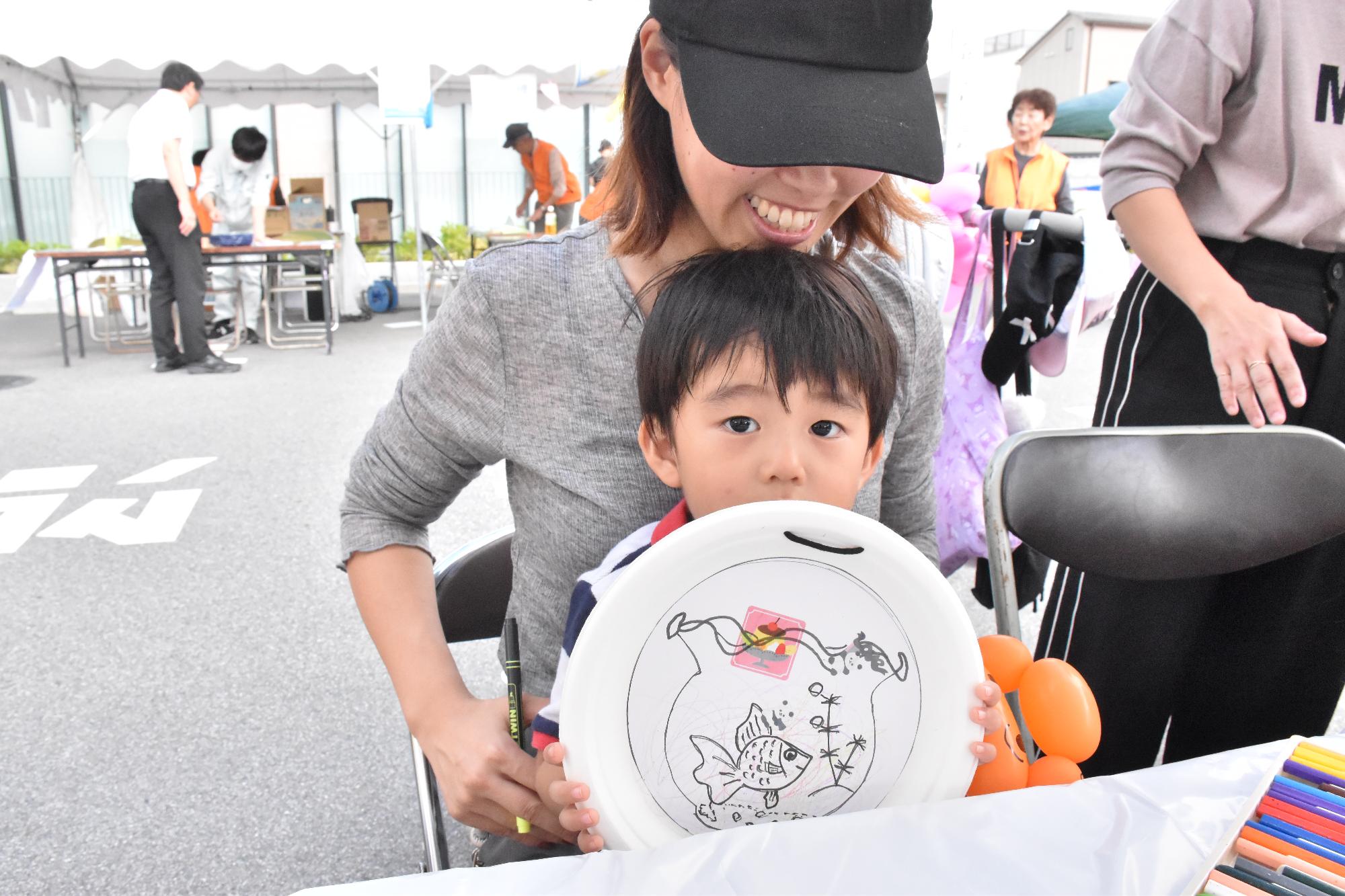 シルバーの日まつり 塗り絵で完成した作品を見せる子ども