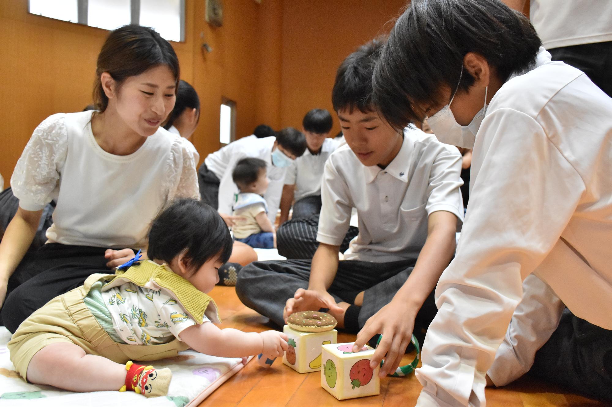 乳幼児とおもちゃで遊ぶ中学生