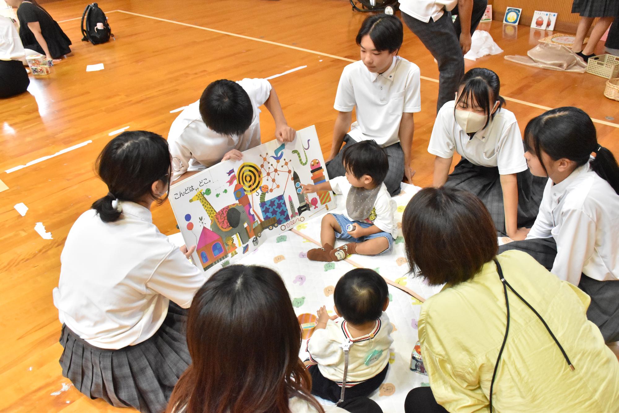 乳幼児に絵本の読み聞かせをする中学生