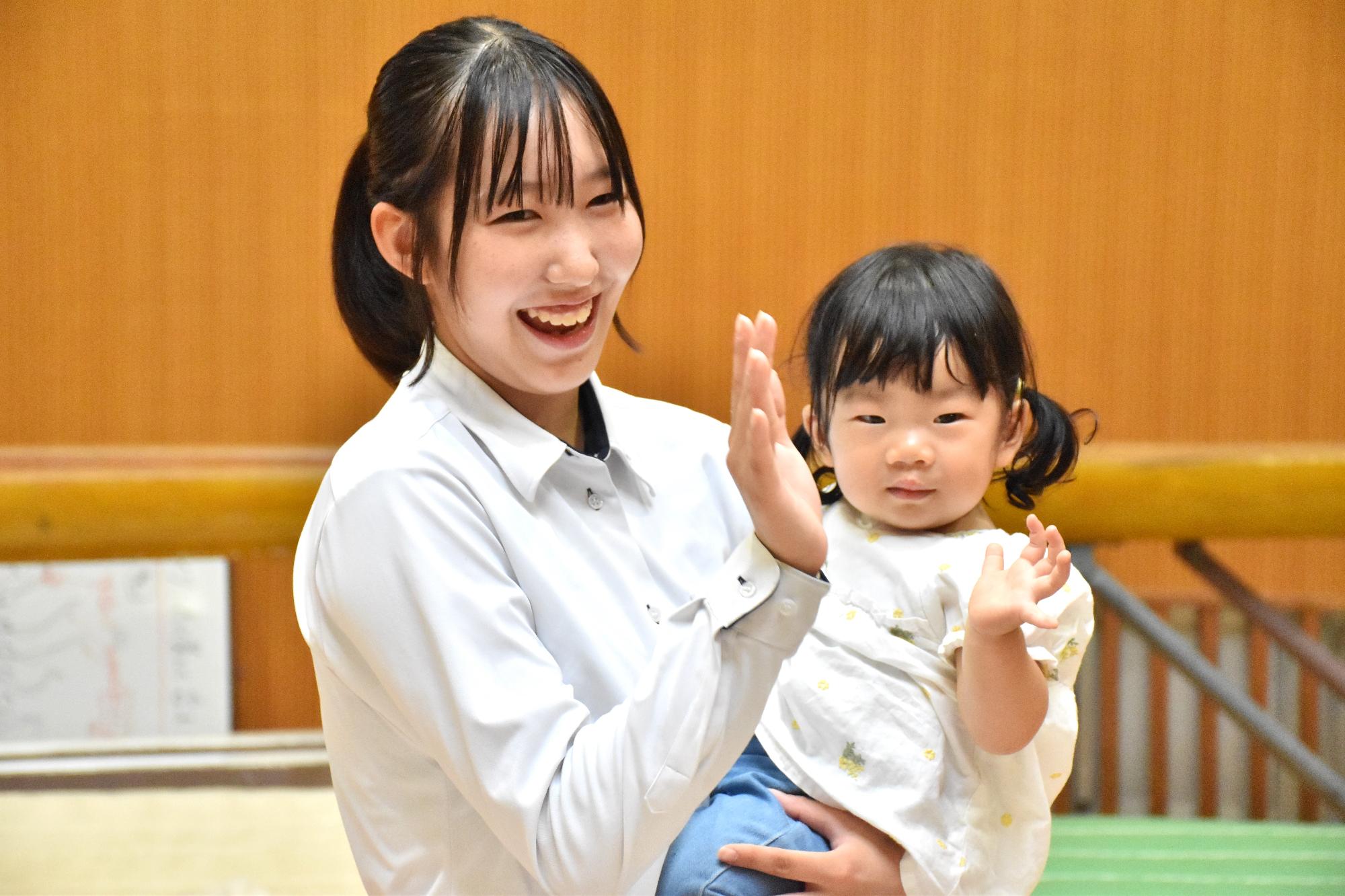 乳幼児を抱き上げる中学生