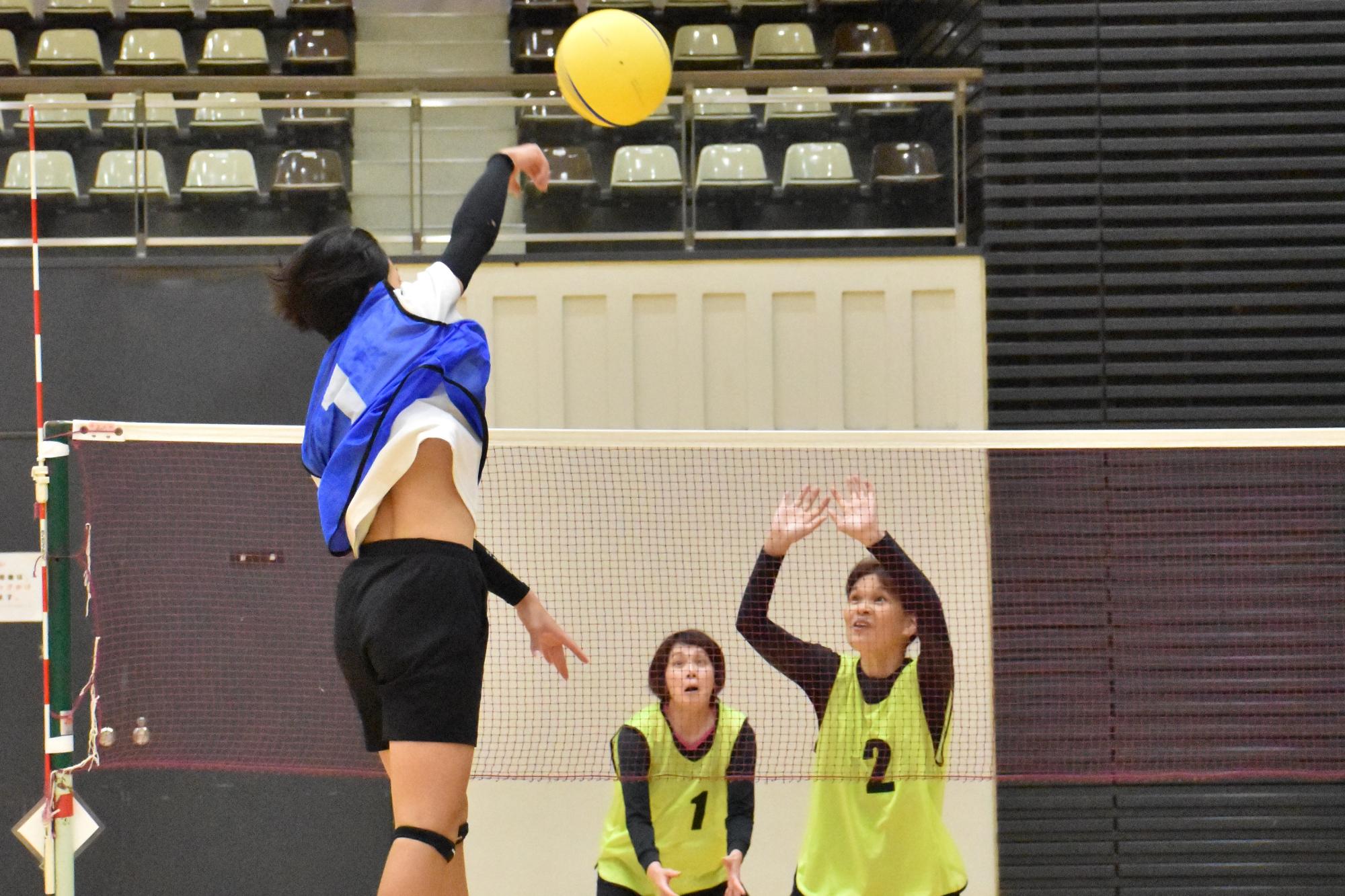 自治会ソフトバレーボールで勢い良くボールを打つ男性