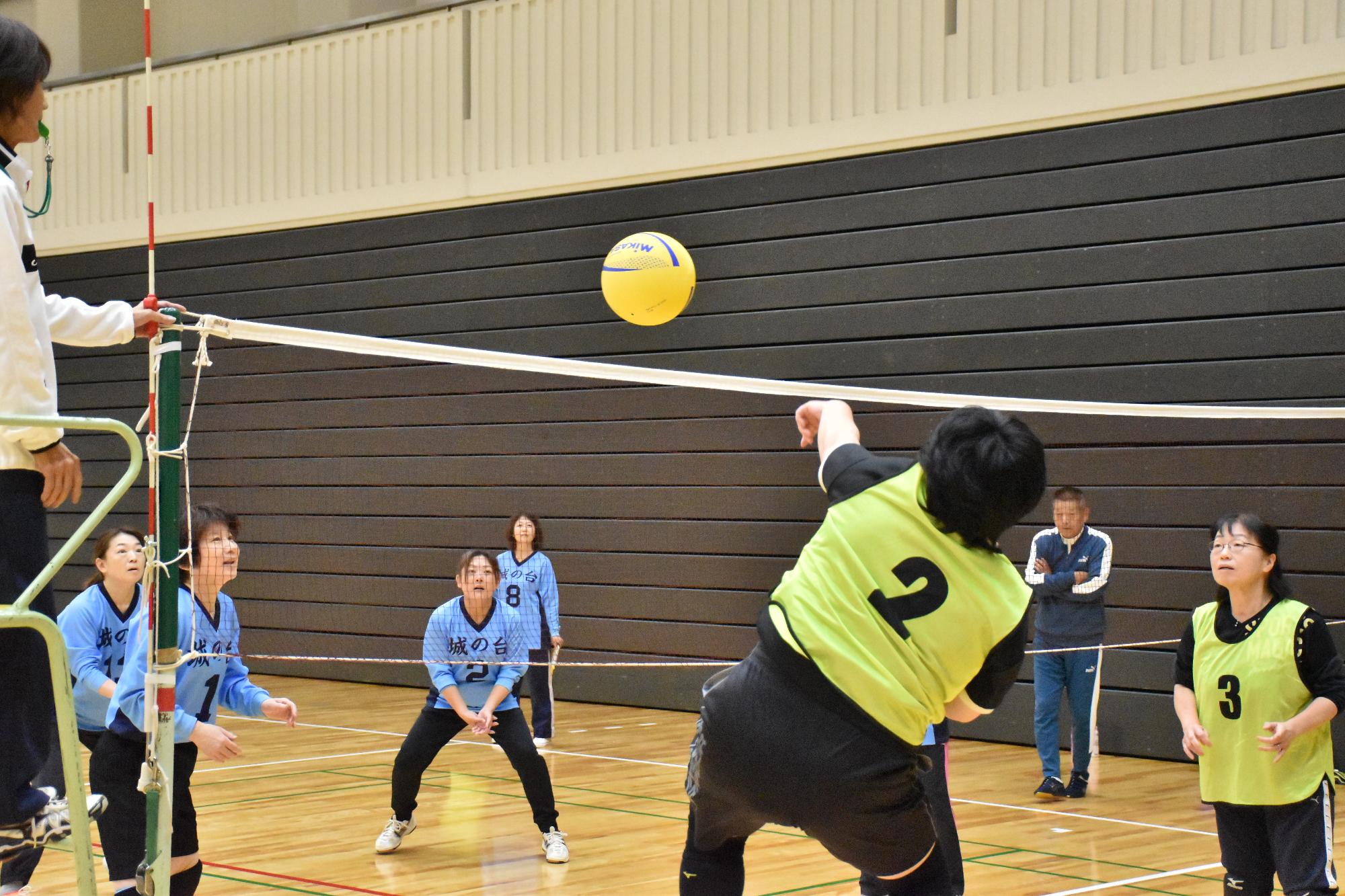 自治会ソフトバレーボールで勢い良くボールを打つ女性