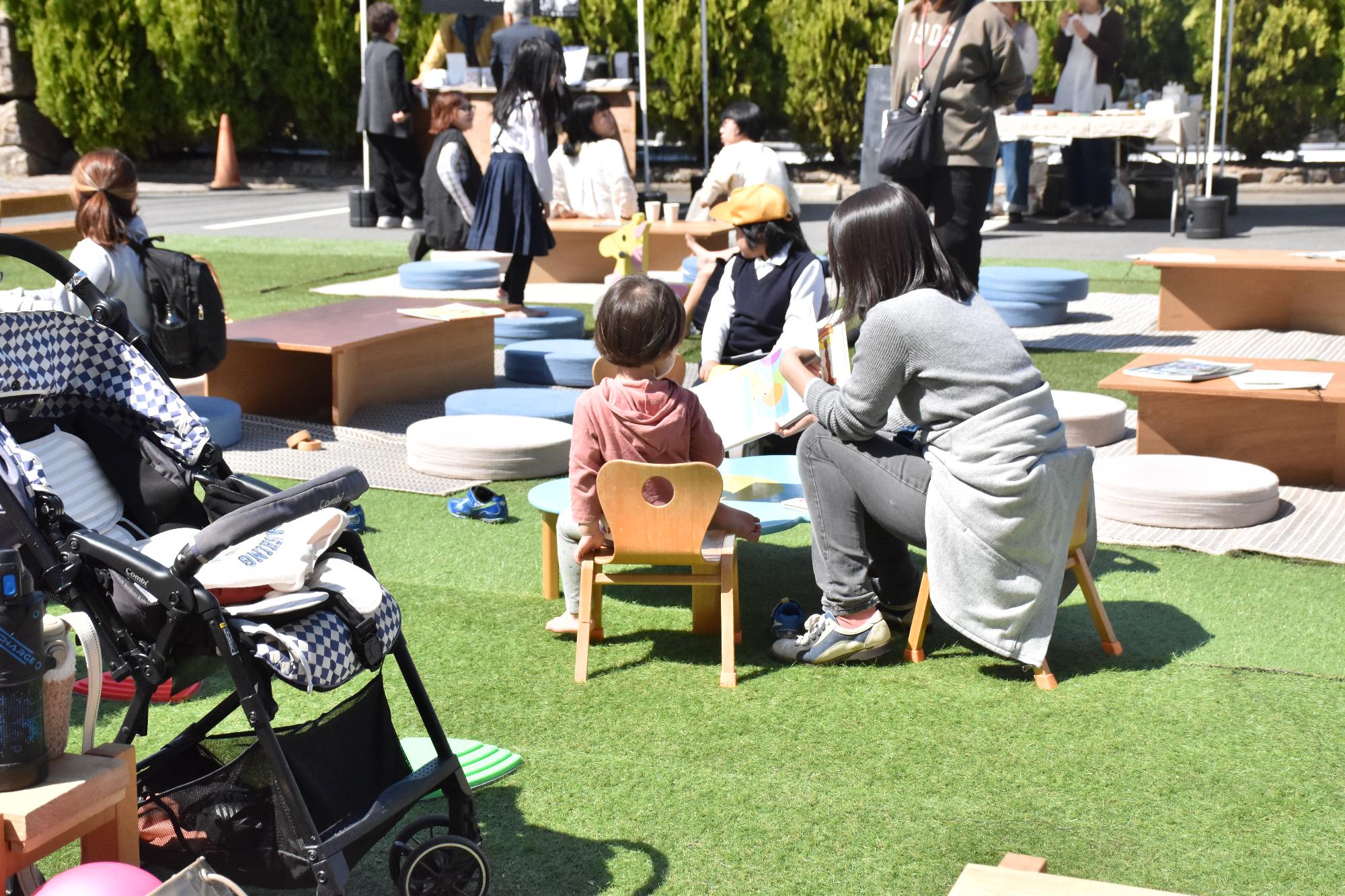 親子で椅子に座りながら一緒に絵本を読んでいる様子