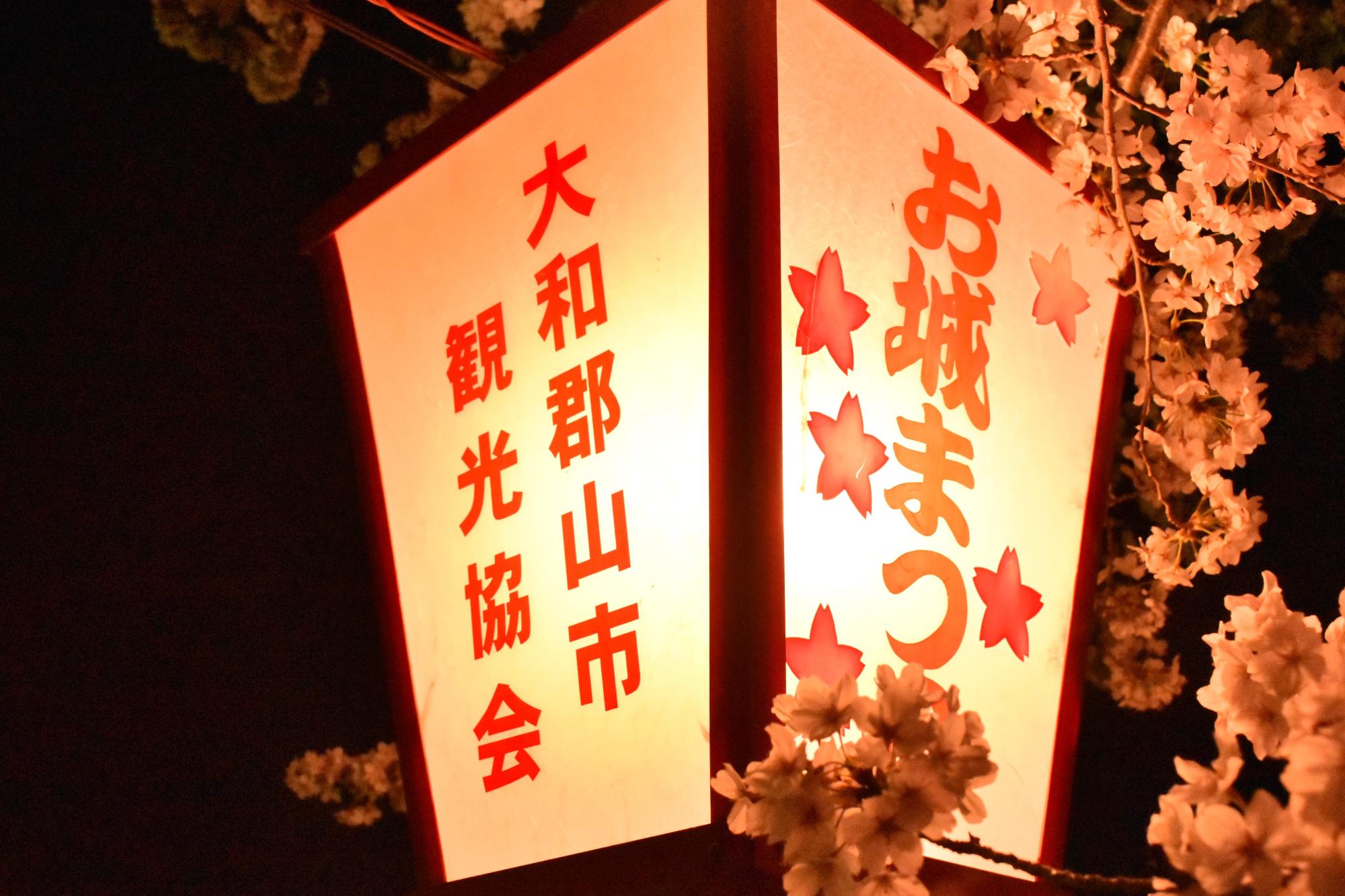お城まつりのぼんぼりの周りを桜が囲んでいる様子