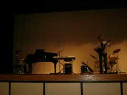 舞台の上で、ピアノを弾く女性とギターを弾く男性の写真