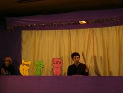 新町保育園の屋内に設置された人形劇のステージで男性が雰囲気を和ませている写真
