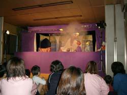 人形劇中に煙が出るシーンに沸く子供たちと保護者の写真