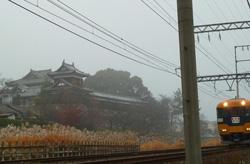 朝霧の中追手東隅櫓の横を走る近鉄特急の写真