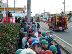 走り去る後姿の消防車を見ている子供たちの写真