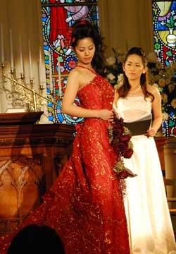 ステンドグラスがある部屋で白いドレスを着た女性の前で赤いドレスを着た女性がポーズをとる写真
