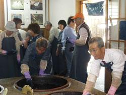 ゴム手袋を付けて釜で作業する人々の写真