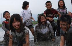 泥んこまみれで笑っている子供たちの写真