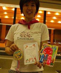 参加賞のメダル、賞状、シャボン玉セットを持った笑顔の女性の写真