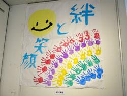絆と笑顔という文字と、太陽と手形を描いている作品の写真