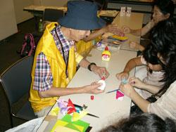 金魚の折り紙を体験するボランティアガイドと子どもたちの写真
