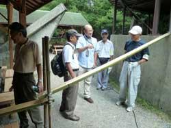 流しそうめんの竹の奥に数名の男性が集って話している様子の写真
