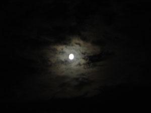 雲の間からこっそりと顔を出したお月様の様子の写真