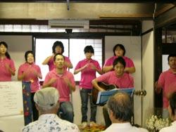 ピンク色のTシャツを着て歌を演奏する人々の写真