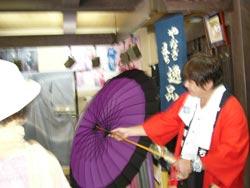 紫色の和傘を広げて説明する北谷呉服店の方の写真