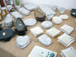 机の上に並べられた皿や茶碗の陶芸作品の写真