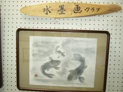3匹の魚のえが書かれた水墨画が壁の中心に飾られている写真