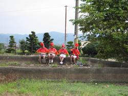 石段に座っている赤い衣装を着た4人の女性の写真